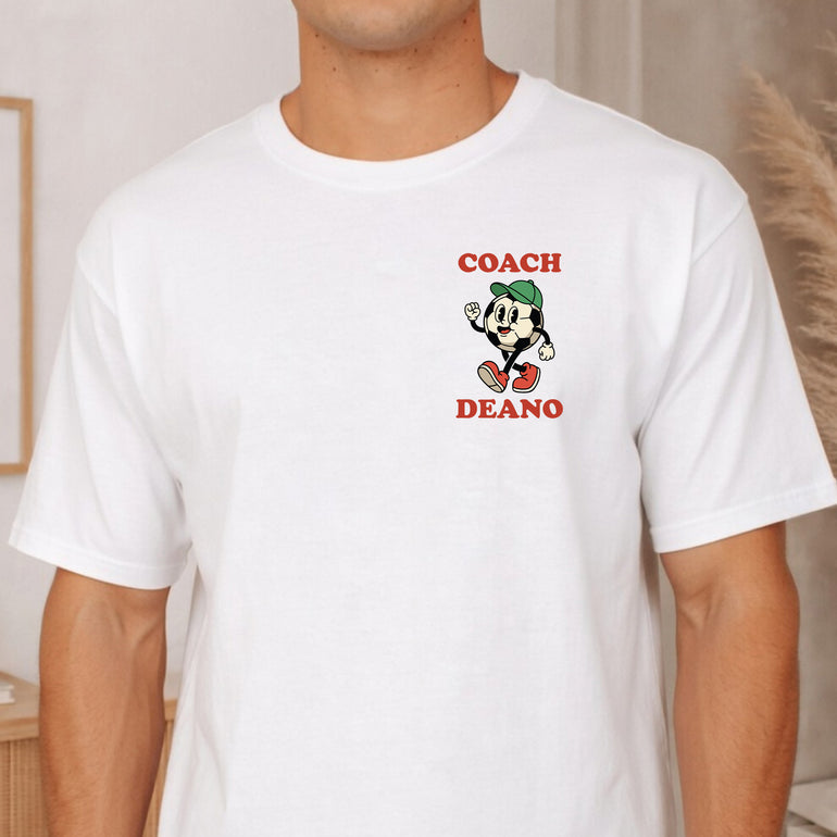 Front of a white Cool Coach Club football coach gift T-shirt with a small Coach Deano badge and a retro cartoon football character on the chest
