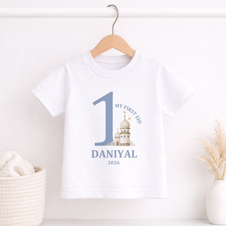 White t-shirt with 'My First Eid' design on a wooden hanger against a white background