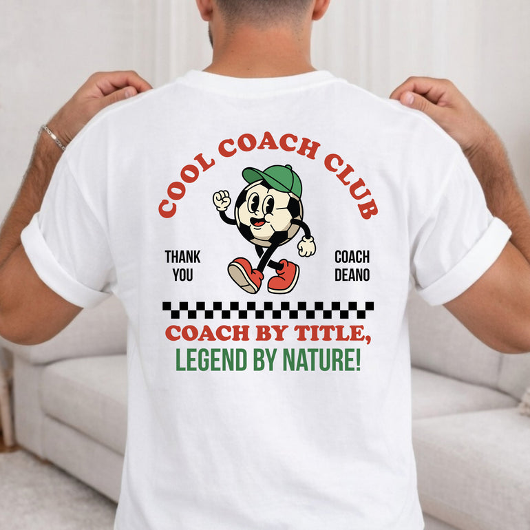 Back of a white Cool Coach Club football coach gift T-shirt printed with Cool Coach Club, a retro cartoon football character in a green cap, Thank You, Coach Deano and Coach by Title, Legend by Nature