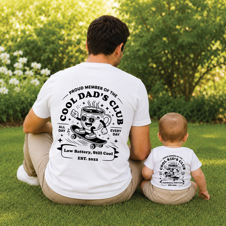 Father and child wearing matching white Cool Dad’s Club T-shirts for Father’s Day.