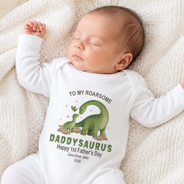 Baby wearing personalised Daddysaurus First Father’s Day baby grow with dinosaur design.