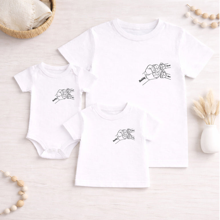 White Daddy T-shirt with two child names and small black fist bump line art design.