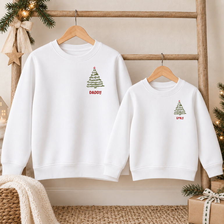 Two white Christmas Crew family jumpers showing the front with a small Christmas tree and the names Daddy and Emily