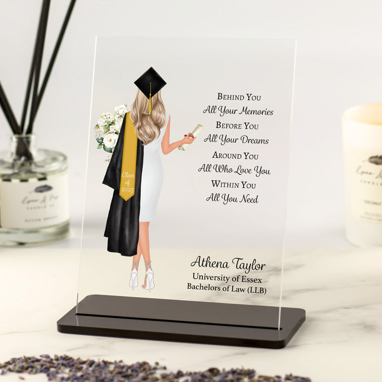 Personalised graduation gift acrylic plaque with floral design, custom name, poem, and graduate illustration holding scroll and flowers on desk display.