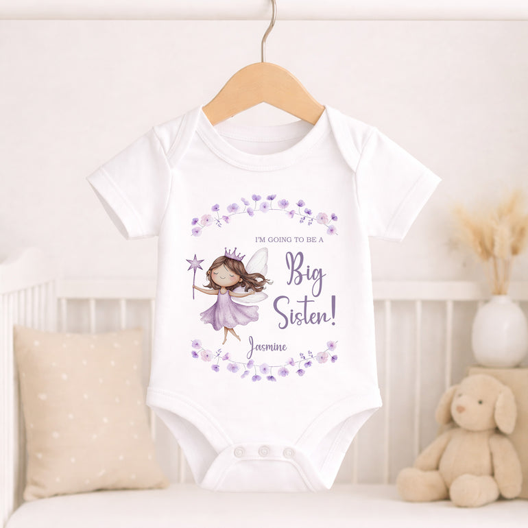 Personalised big sister baby vest with lavender fairy design, floral wreath and child’s name hanging in a neutral nursery.