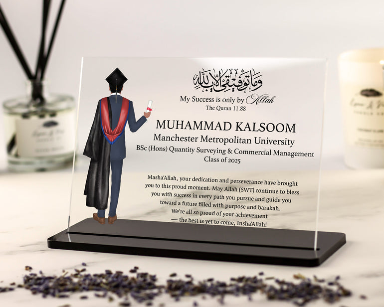 Graduation-themed personalized plaque with a person in a graduation gown on a stand, placed on a surface with decorative items.