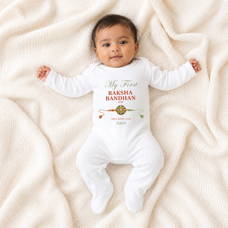 Baby wearing a white My First Raksha Bandhan baby grow personalised with Aarav, the year 2026 and a traditional rakhi.
