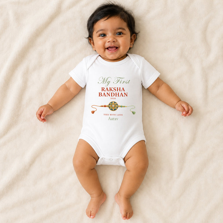 Smiling baby wearing a white personalised My First Raksha Bandhan vest with Aarav, the year 2026 and a traditional rakhi.
