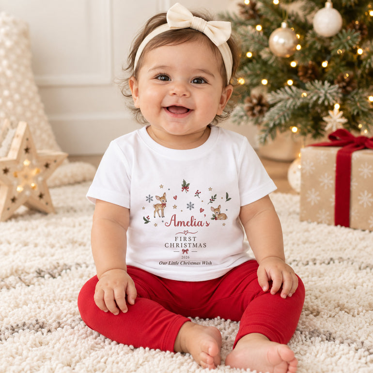 Baby wearing personalised First Christmas T-shirt with festive reindeer design, name Amelia, chosen year and Little Christmas Wish wording