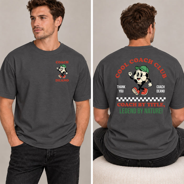 Man in a charcoal Cool Coach Club football coach gift T-shirt, the back printed with Cool Coach Club, a retro cartoon football character in a green cap, Thank You, Coach Deano and Coach by Title, Legend by Nature, the front with a small Coach Deano badge