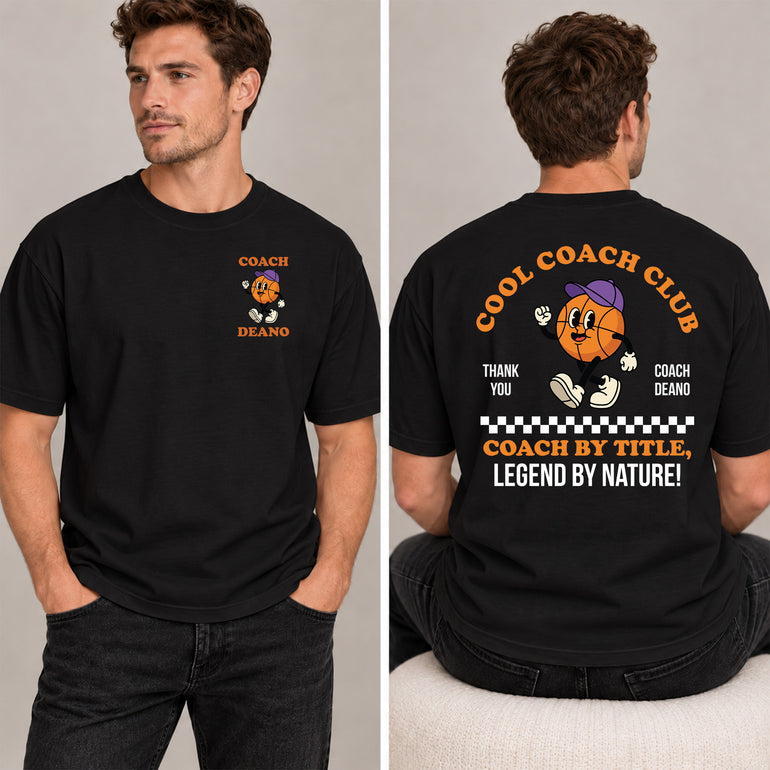 Man in a black Cool Coach Club basketball coach gift T-shirt, the back printed with Cool Coach Club, a retro cartoon basketball character in a purple cap, Thank You, Coach Deano and Coach by Title, Legend by Nature, the front with a small Coach Deano badge