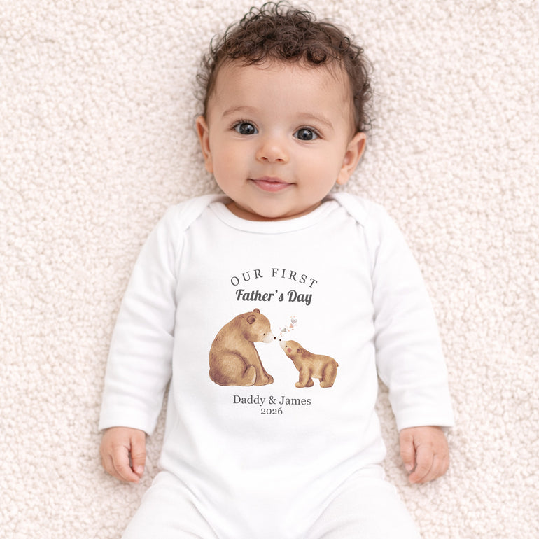 Baby wearing personalised Our First Father’s Day baby grow with watercolour bear and cub illustration.
