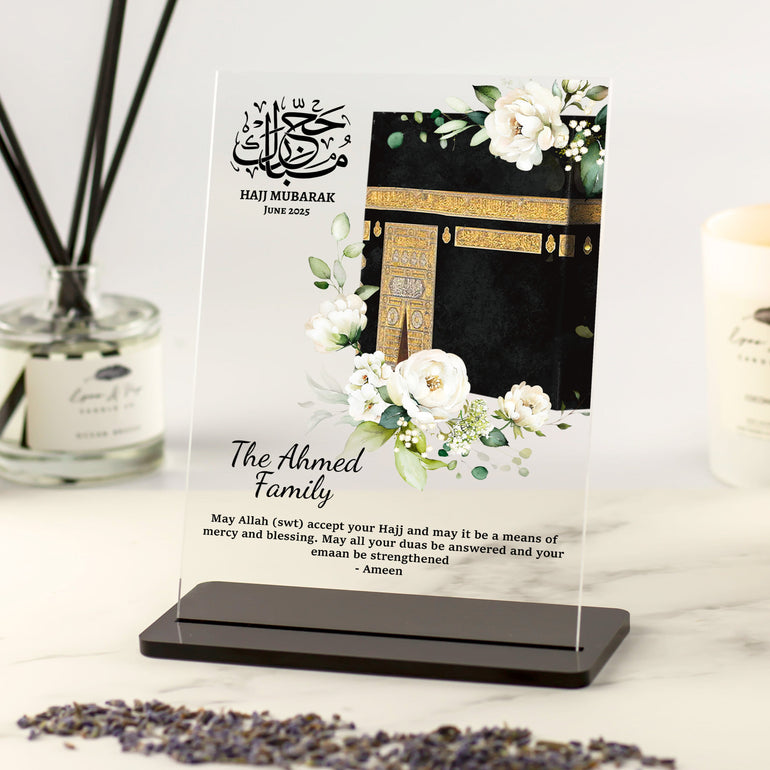 Personalised Hajj Mubarak acrylic plaque with Kaaba illustration, white floral accents, and custom family name and dua in elegant black font.