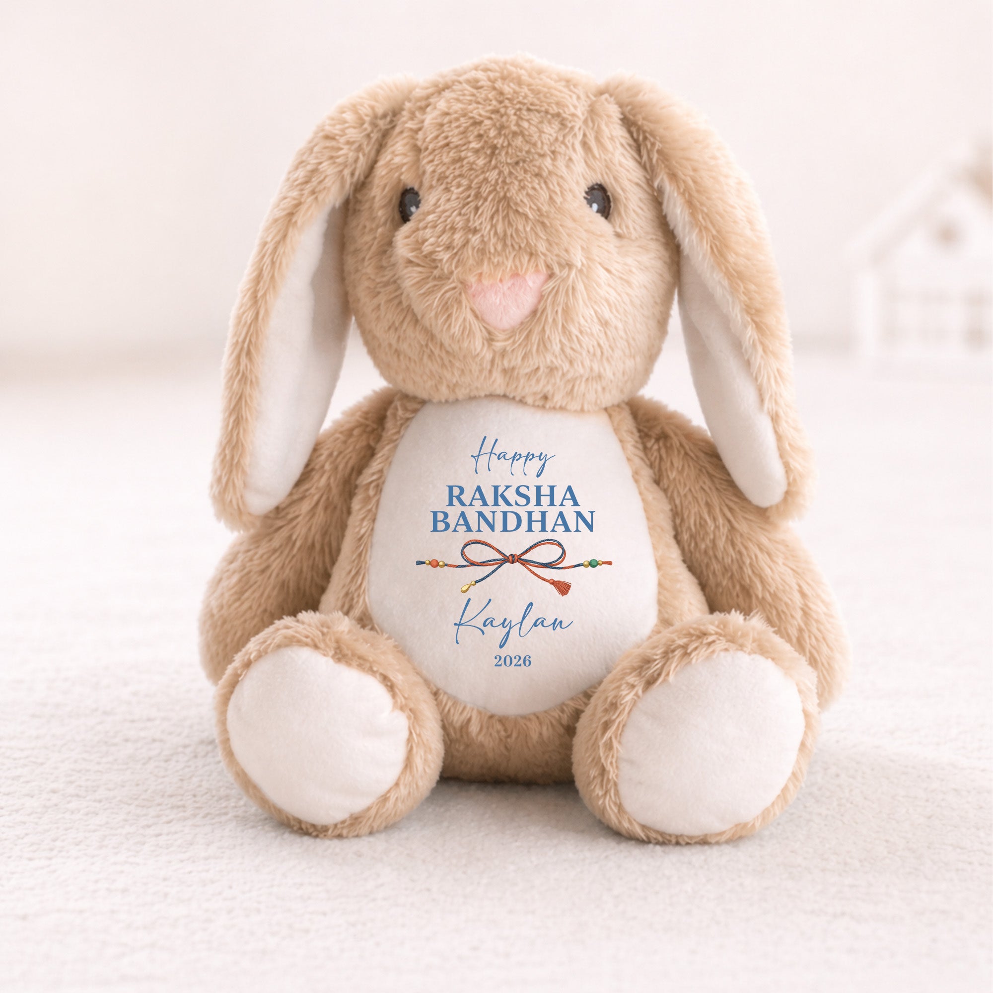 Neutral bunny personalised with Happy Raksha Bandhan, the name Kaylan, a traditional rakhi and the year 2026.
