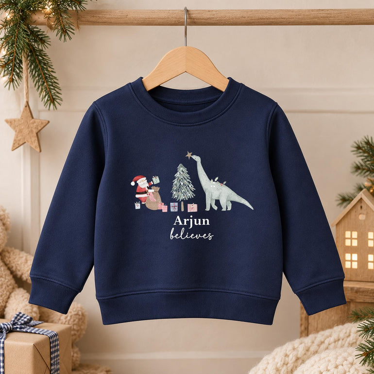 Navy kids dinosaur Christmas jumper on a hanger with the Santa and dinosaur design and a name in white