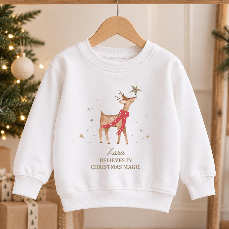 White kids reindeer Christmas jumper on a hanger with the gold star design and gold lettering