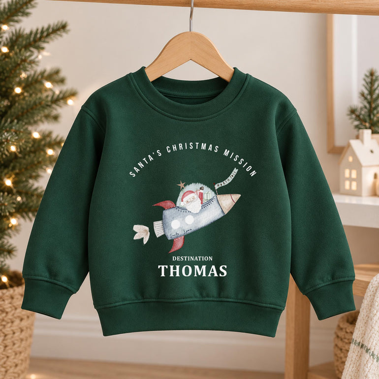 Forest green kids Christmas jumper on a hanger printed with Santa's Christmas Mission, a rocket and Destination above a name