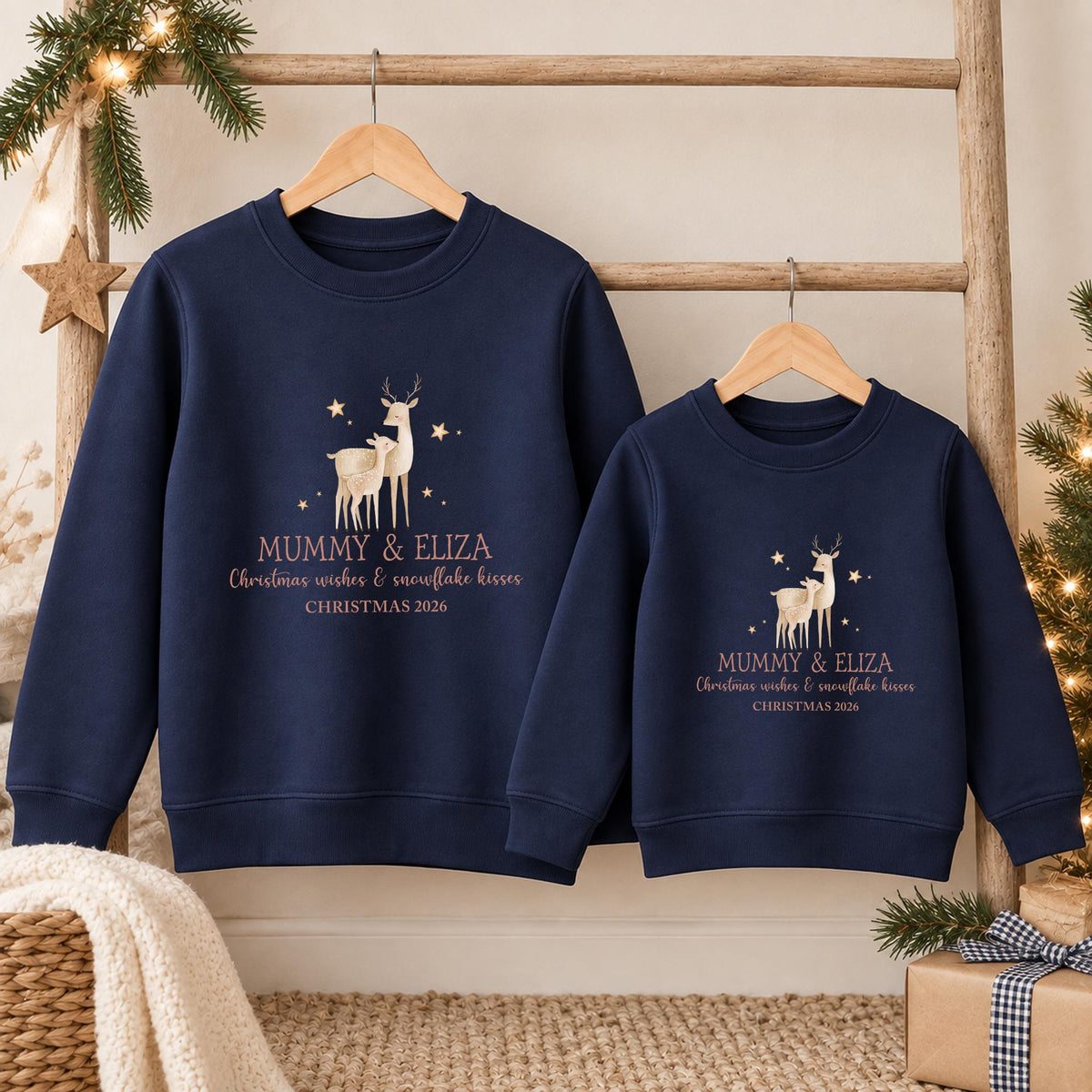 Navy adult and child mini me Christmas jumpers side by side, each with a reindeer and fawn, two example names in gold, Christmas wishes and snowflake kisses and an example year
