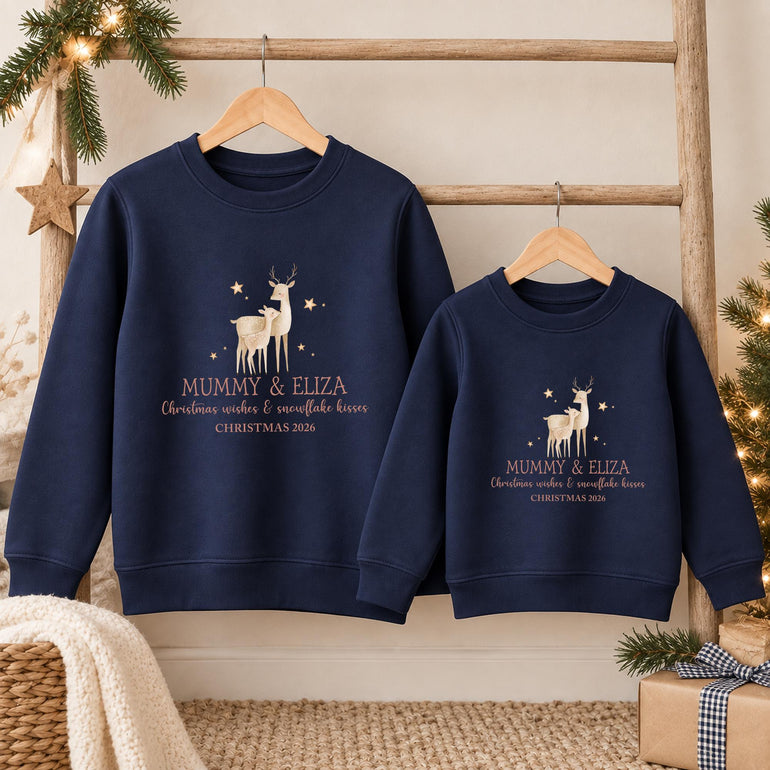 Navy adult and child mini me Christmas jumpers side by side, each with a reindeer and fawn, two example names in gold, Christmas wishes and snowflake kisses and an example year