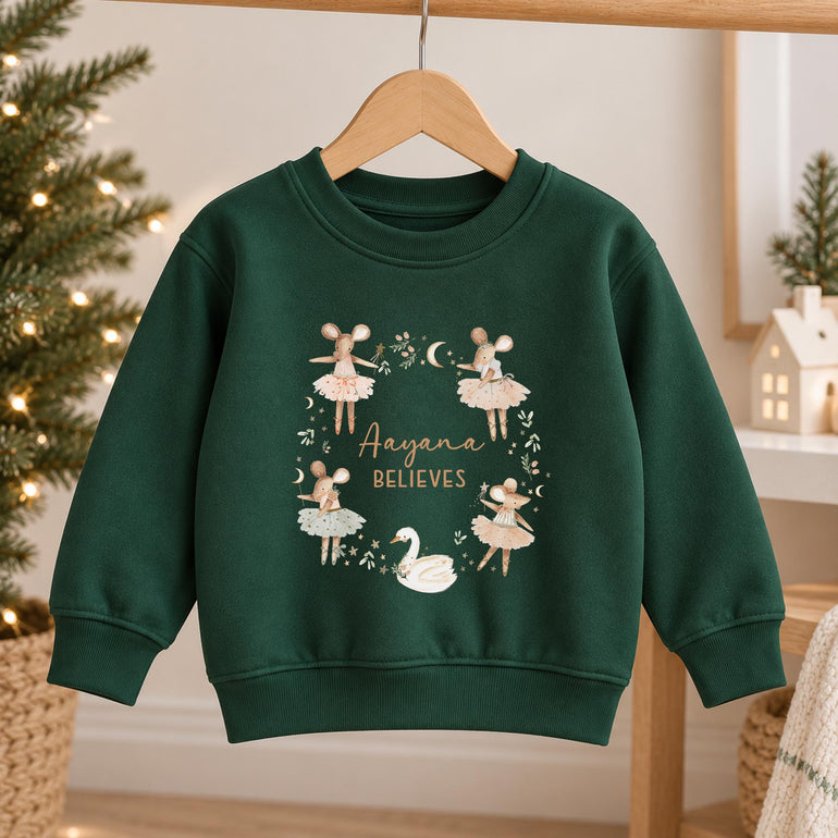 Forest green girls Christmas jumper on a hanger, with the ballerina mice and swan wreath around a name and the word Believes