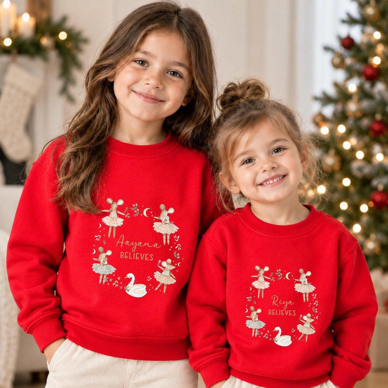 Two young sisters beside a Christmas tree in matching red ballerina mice Christmas jumpers, each personalised with a name