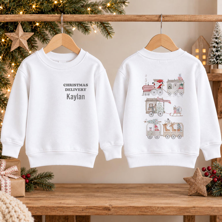 White kids Santa train Christmas jumper shown front and back on hangers, with grey lettering on the front and the Santa train with presents on the back