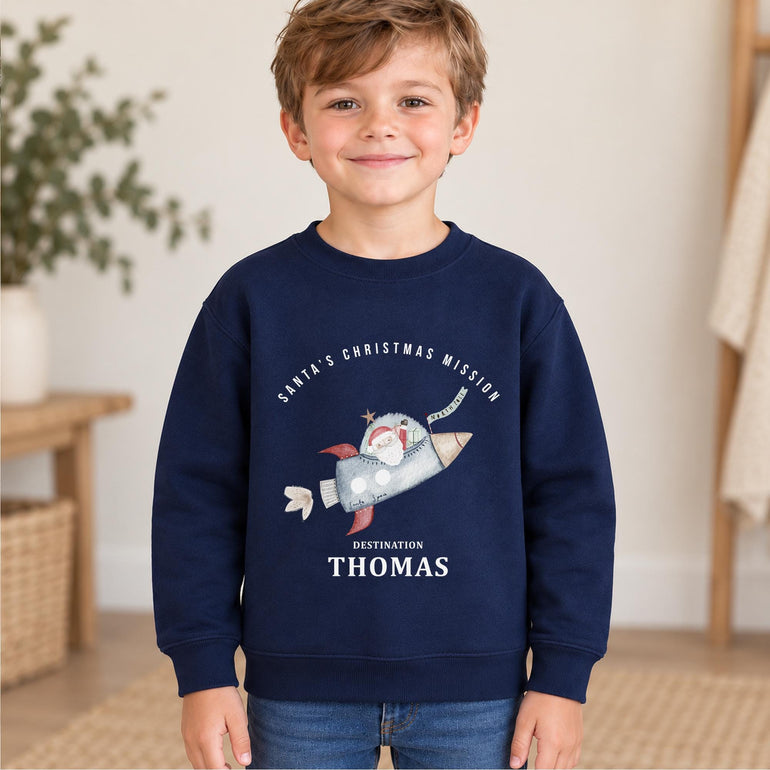Boy wearing a navy personalised Santa rocket Christmas jumper with his name in white lettering