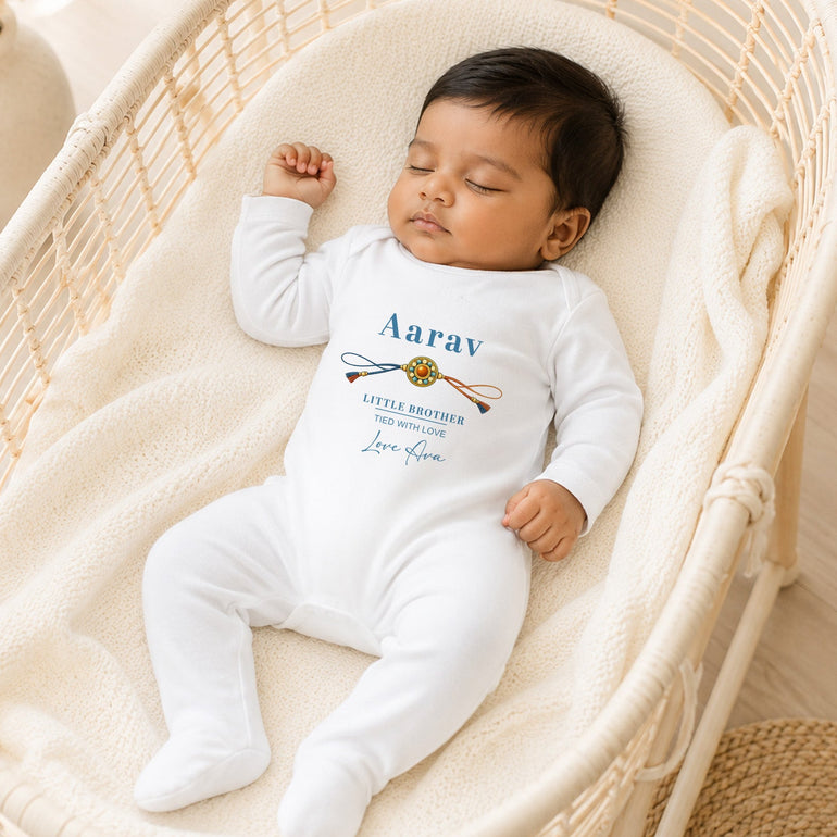 Sleeping baby wearing a white personalised Little Brother Raksha Bandhan baby grow with the name Aarav and Love Ava message.
