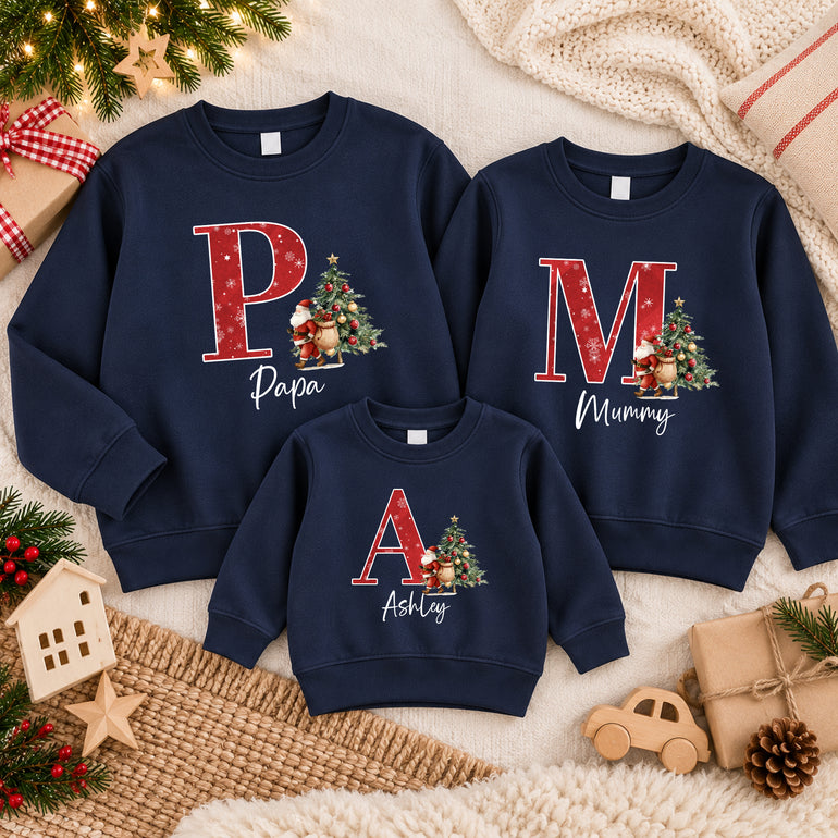 Family in navy custom Christmas jumpers each with a large red initial, a Santa and Christmas tree, and the names Papa, Mummy and Ashley