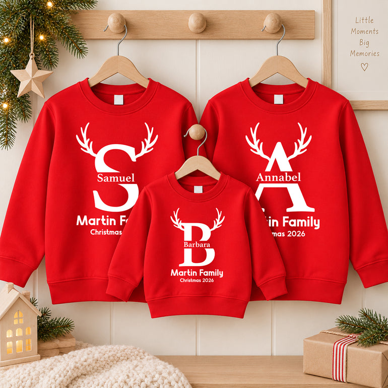 Family in red matching Christmas jumpers each with a large white initial with reindeer antlers, their name, Martin Family and Christmas 2026
