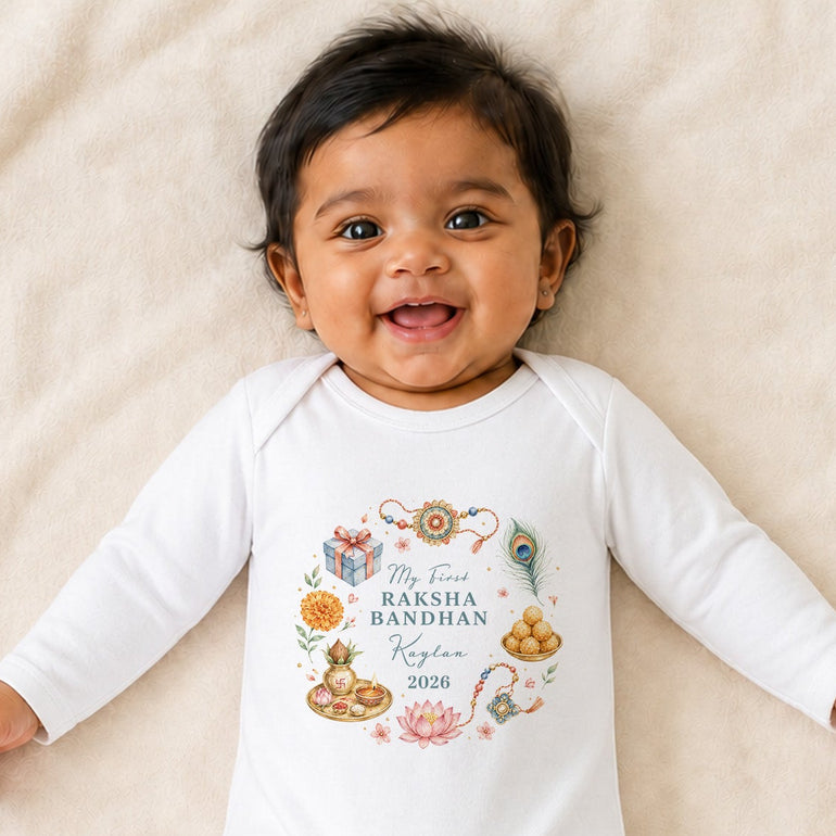Smiling baby wearing a white personalised My First Raksha Bandhan baby grow with a colourful festival wreath, name and year.
