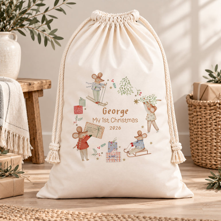 Cream personalised first Christmas sack with winter mice, George’s name and My 1st Christmas 2026 wording, displayed in a neutral room.