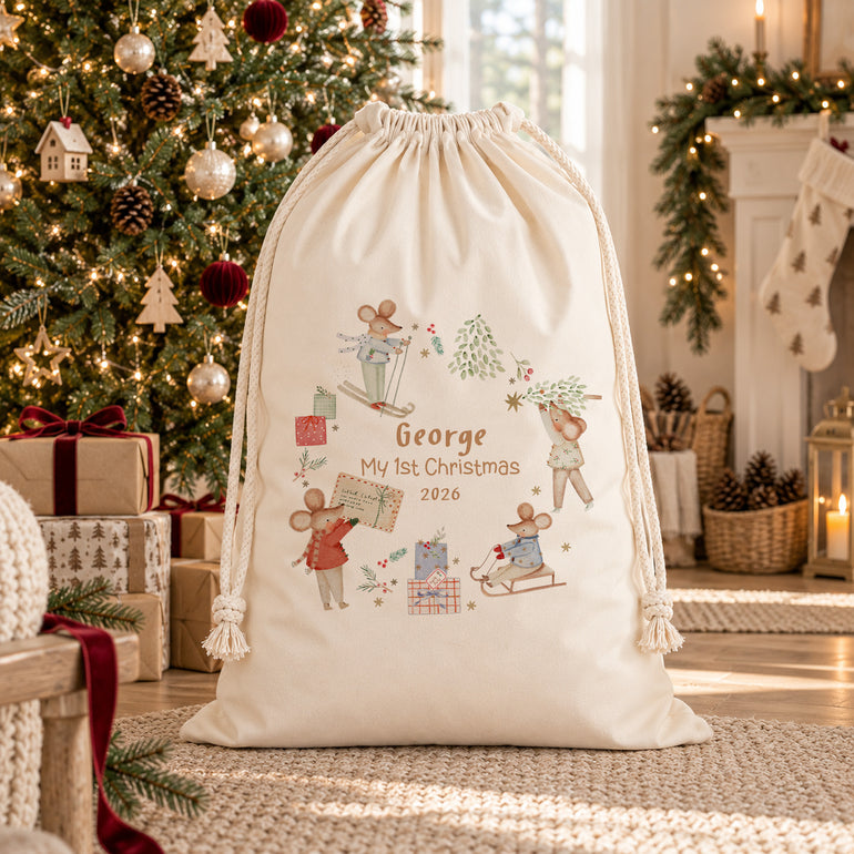 Personalised My 1st Christmas sack with festive mice, a name and year, displayed beside a decorated Christmas tree.