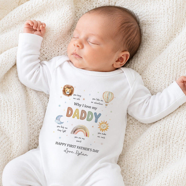 Baby wearing personalised Why I Love My Daddy Father’s Day baby grow with adventure motifs and Happy First Father’s Day wording.
