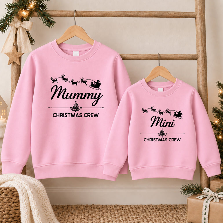 Mum and daughter in matching light pink Mummy and Mini Christmas Crew jumpers with Santa's sleigh