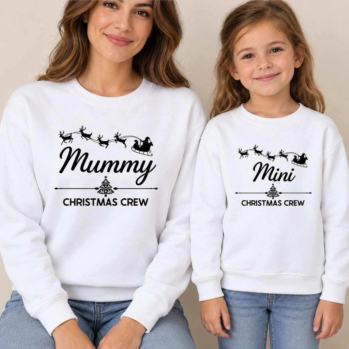 Mum and daughter in matching white Christmas jumpers reading Mummy Christmas Crew and Mini Christmas Crew with Santa's sleigh and reindeer