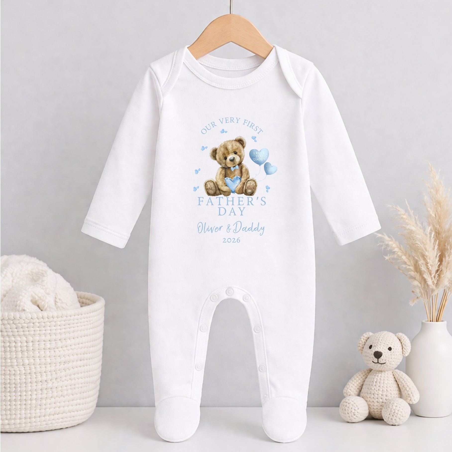 White baby grow 1st Father's Day with teddy bear design on a hanger against a light gray background.